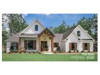 White farmhouse exterior with brown accents and a landscaped lawn at 295 Tradition Dr, Mount Gilead, NC 27306