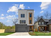 Striking modern home featuring a three-story design with a gray garage door, wood facade, and landscaped yard at 3132 Carol Ave, Charlotte, NC 28208