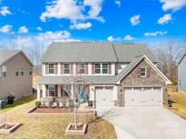 Two-story house with stone accents, three-car garage, and landscaped yard at 7405 Bosson Sw St, Concord, NC 28025