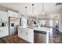 Modern kitchen with stainless steel appliances, white cabinets and hardwood floors blends into the dining and living area at 128 Shay Crossing Rd, Salisbury, NC 28146
