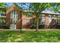 Brick townhome exterior with well-maintained lawn, mature trees and steps leading up to the front door at 128 Steinbeck Way # E, Mooresville, NC 28117