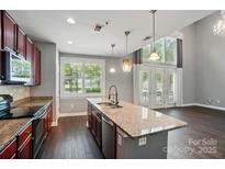Bright, open kitchen with an island, stainless steel appliances, and a view to the living area with soaring ceilings at 128 Steinbeck Way # E, Mooresville, NC 28117