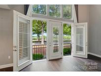Bright living room featuring french doors that open to a cozy balcony overlooking manicured grounds and lush trees at 128 Steinbeck Way # E, Mooresville, NC 28117