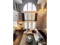 Spacious living room features a large window, hardwood floors, and a stylish chandelier at 128 Steinbeck Way # E, Mooresville, NC 28117