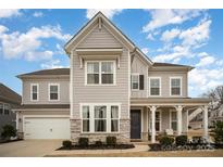 Two-story house with gray siding, stone accents, and a front porch at 15421 Keyes Meadow Way, Huntersville, NC 28078