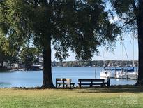 Picturesque waterfront view with benches, mature trees, and boats docked nearby at 16721 Spinnaker Ln, Cornelius, NC 28031