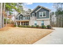 Striking two-story home featuring a brick and shingle exterior, mature trees and a well-manicured lawn at 109 Belfry Loop, Mooresville, NC 28117