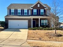 Charming two-story home featuring a two-car garage, brick accents, blue shutters and a well-manicured front yard at 121 Mackinac Dr, Mooresville, NC 28117