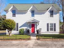 Charming white two-story home with red door, black fence, and landscaping at 301 S Washington St, Monroe, NC 28112