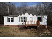 White single-wide mobile home with wood deck and landscaped yard at 3300 Bendwood Rd, Newton, NC 28658