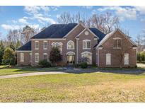 Stately brick home featuring a well-manicured lawn, arched windows, and a classic architectural design at 4316 Mourning Dove Dr, Matthews, NC 28104