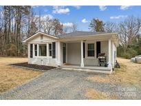 Charming single-story home featuring a cozy front porch, updated exterior paint, and a well-maintained gravel driveway at 5483 Paulmo Dr, Charlotte, NC 28216