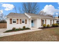 Charming white brick home featuring a light blue door, wood shutters, and manicured landscaping at 11400 Five Cedars Rd, Charlotte, NC 28226