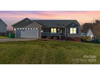 Ranch style home with attached garage and landscaped lawn at 1243 Glory Ct, Oakboro, NC 28129