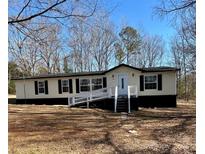 Charming single-story home with a ramp and traditional black shutters, set against a backdrop of mature trees at 137 S Penny St, Lancaster, SC 29720