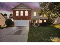 Brick two-story house with a two-car garage and landscaped lawn at 145 Ashton Woods Ct, Mount Holly, NC 28120