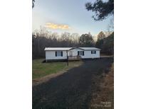 Single-story home with a metal roof and a gravel driveway, nestled in a wooded setting at 145 Morcroft Ln, Cleveland, NC 27013