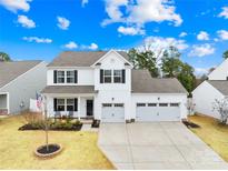 Charming two-story home featuring a spacious three-car garage and a welcoming front porch with rocking chairs at 191 Sutters Mill Dr, Troutman, NC 28166