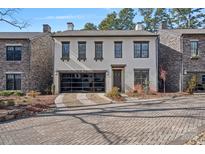 Craftsman style home with stone and stucco exterior, a glass garage door, and a brick driveway at 220 Ambleside Village Ln, Davidson, NC 28036