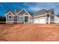 New construction home featuring gray siding, stone accents, and a two-car garage, set against a blue sky at 6098 Ballard Rd, Denver, NC 28037