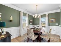 Formal dining room with a round table, four chairs, and green walls with white wainscoting at 821 Bethesda Rd, Statesville, NC 28677