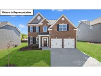 Two-story brick home with three-car garage and landscaped lawn at 1033 Merganser Way, Indian Trail, NC 28079