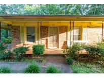 Charming brick home featuring a covered front porch with mature landscaping and a secure front door at 3581 Thompson St, Newton, NC 28658