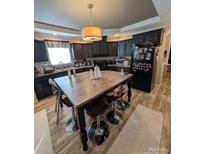 Eat-in kitchen features a central island table, dark cabinets, and a modern light fixture at 5122 Wrenn Dr, Denver, NC 28037