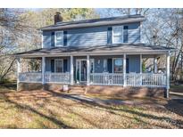 Two-story gray house with a wraparound porch and rocking chairs at 1316 Neal Hawkins Rd, Gastonia, NC 28056