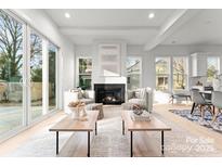 Bright living room featuring a fireplace, light wood floors, and sliding glass doors to the backyard at 2221 Edison St, Charlotte, NC 28206