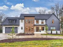 Stunning modern home with gray and white exterior, two-car garage, and landscaped yard at 4039 Abingdon Rd, Charlotte, NC 28211