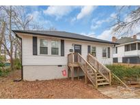 Charming one-story home with white siding, black shutters and inviting wooden stairs to front door at 65 Franklin St, Wadesboro, NC 28170