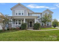 Two-story home with gray siding, stone accents, and a landscaped lawn at 9635 Andres Duany Dr, Huntersville, NC 28078