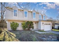 Tan two-story home featuring symmetrical dormer windows and an attached one car garage at 10718 Downpatrick Pl, Charlotte, NC 28262