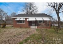 Charming brick home featuring awning-covered windows and a welcoming front porch at 1648 Newton Dr, Statesville, NC 28677