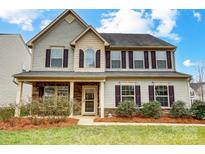 Charming two-story home featuring stone accents, a covered front porch, and well-maintained landscaping at 2727 Cypress Oak Ln, Gastonia, NC 28056