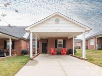 Charming single-story brick home with a covered carport and inviting red Adirondack chairs at 3867 Azalea Trl, Denver, NC 28037