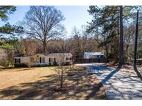 Charming single-story home with mature trees, a long driveway, and fenced storage in a tranquil, wooded setting at 4428 Turkey Ln, Rock Hill, SC 29730