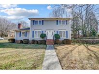 Two-story home featuring blue shutters, brick chimney and entrance, and neatly manicured landscaping at 7707 Ritter Dr, Charlotte, NC 28270