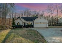 Charming single-story home with well-manicured lawn, mature trees, and attached two-car garage at 781 Woodlawn Ave, Mount Holly, NC 28120