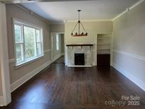 Spacious living room with hardwood floors and a brick fireplace at 105 N Inman Ave, Bessemer City, NC 28016