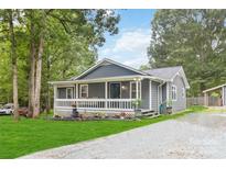 Charming gray home with a welcoming porch and landscaped front yard and gravel driveway at 107 Deese Ct, Indian Trail, NC 28079