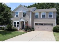 Charming two-story home with attached garage, well-maintained lawn, and mature landscaping at 1128 Tangle Ridge Se Dr, Concord, NC 28025