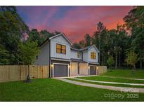 Beautiful home exterior featuring gray siding, stone accents, a well-manicured lawn, and a colorful sunset at 122 I K Beatty St, Charlotte, NC 28214