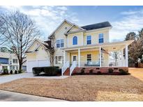 Charming two-story home features a welcoming front porch, attached garage, and landscaped lawn at 15313 Wedgewood Commons Dr, Charlotte, NC 28277