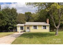 Ranch style home with a yellow exterior, driveway, and landscaped lawn at 1704 Rice Planters Rd, Charlotte, NC 28273