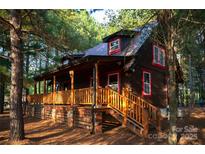 Charming cabin exterior with a wooden porch and stairs surrounded by lush greenery at 3804 Putters Ln, Maiden, NC 28650