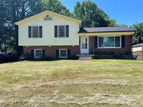 Split-level home with brick and siding exterior, black shutters, front yard and mature trees at 4809 Tanglebriar Dr, Charlotte, NC 28208