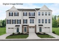 A well-manicured lawn enhances the curb appeal of this three-story townhome with a drive-in garage and a neutral color palette at 2533 Ellen Ave # 1016B, Charlotte, NC 28208