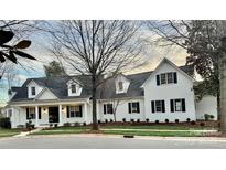 Charming two-story white brick home with a black roof, black shutters and a inviting front porch at 357 Magnolia St, Davidson, NC 28036